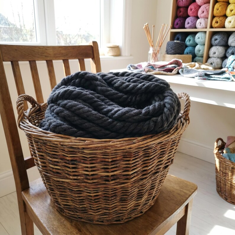 Anthracite giant wool yarn into a basket on a wooden chair.