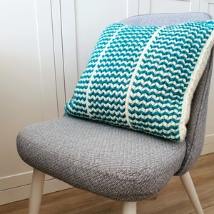 May include: A gray chair with white legs and a teal and white striped pillow.