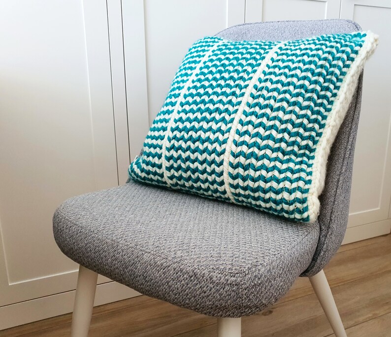 May include: A gray chair with white legs and a teal and white striped pillow.