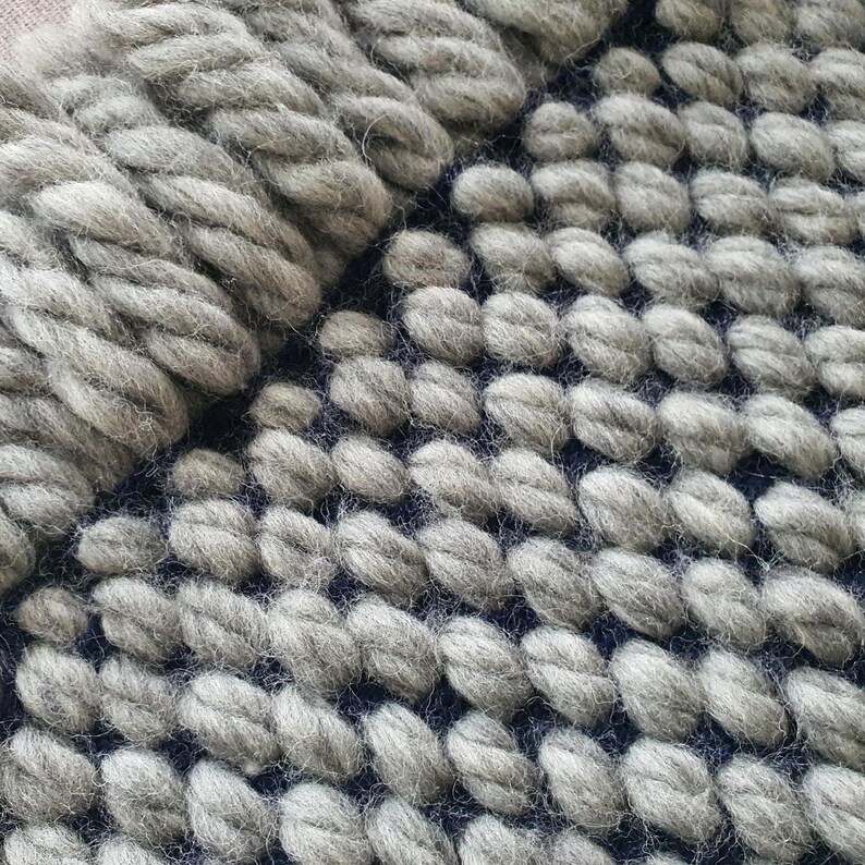Close-up of fringe on wool blanket with twisted ends and dense knit structure.