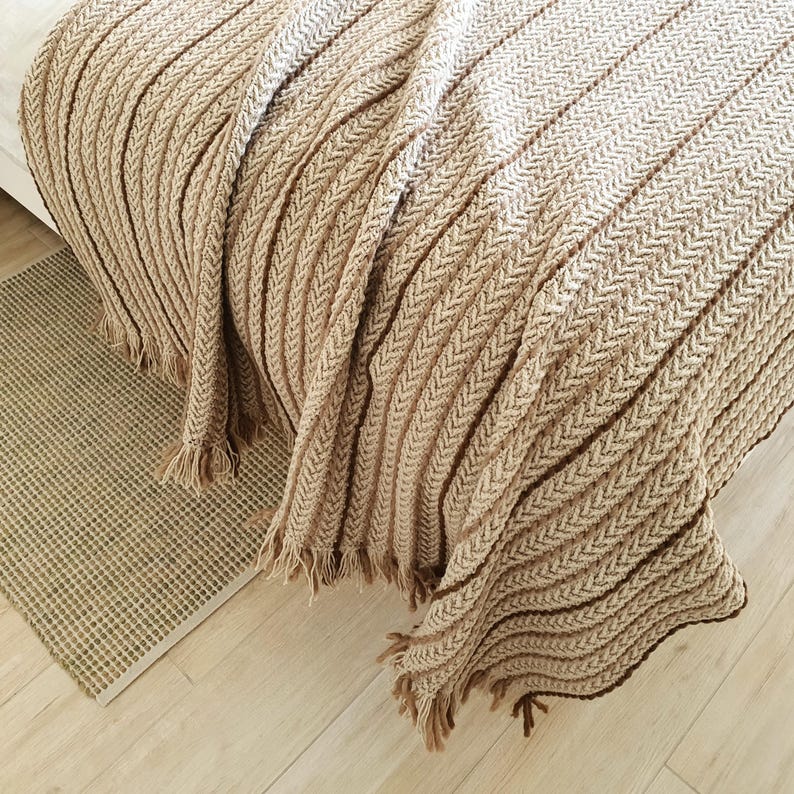 Beige crochet wool blanket placed on a bed, large textured knit throw with natural folds
