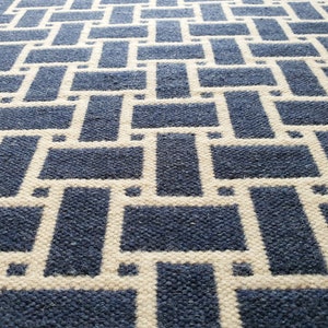 May include: A blue and white woven rug with a geometric pattern. The rug has a textured surface and a modern design.