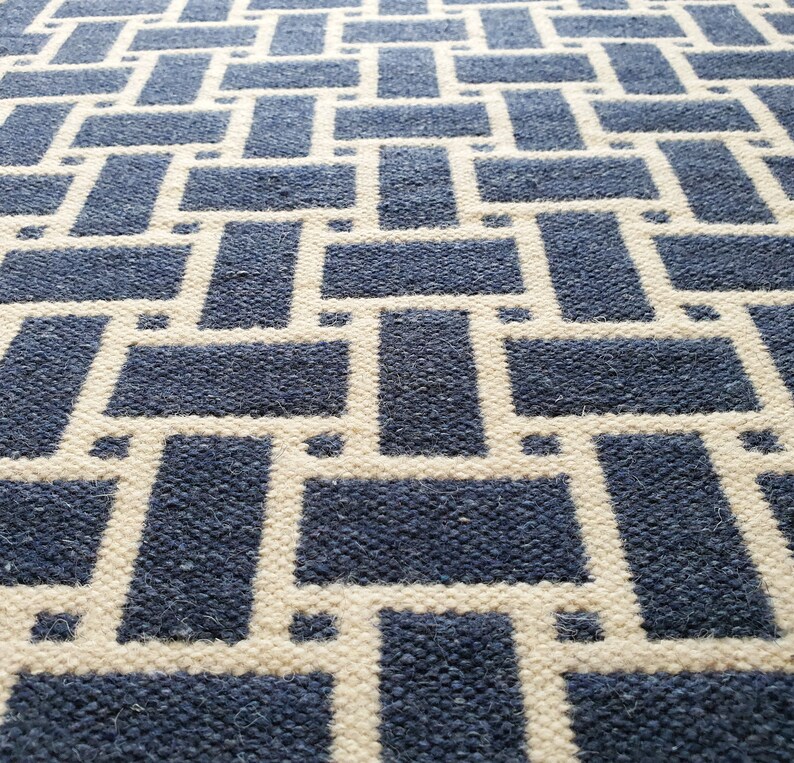 May include: A blue and white woven rug with a geometric pattern. The rug has a textured surface and a modern design.