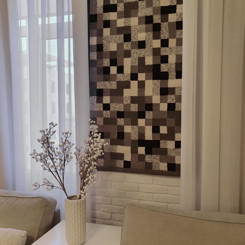 K&ouml;nnte beinhalten: Eine wei&szlig;e Backsteinwand mit einer grauen und schwarzen geometrischen Mustertapete, die daran h&auml;ngt. Eine wei&szlig;e Vase mit einem wei&szlig;en Zweig mit wei&szlig;en Beeren steht vor der Tapete.