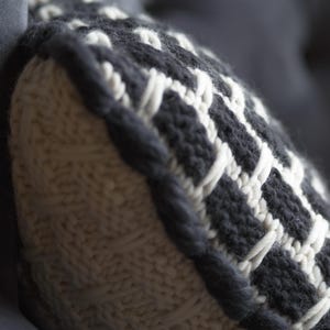 Close up of chunky knit wool texture. Natural breathable fiber cushion cover in white and black yarn for cozy home