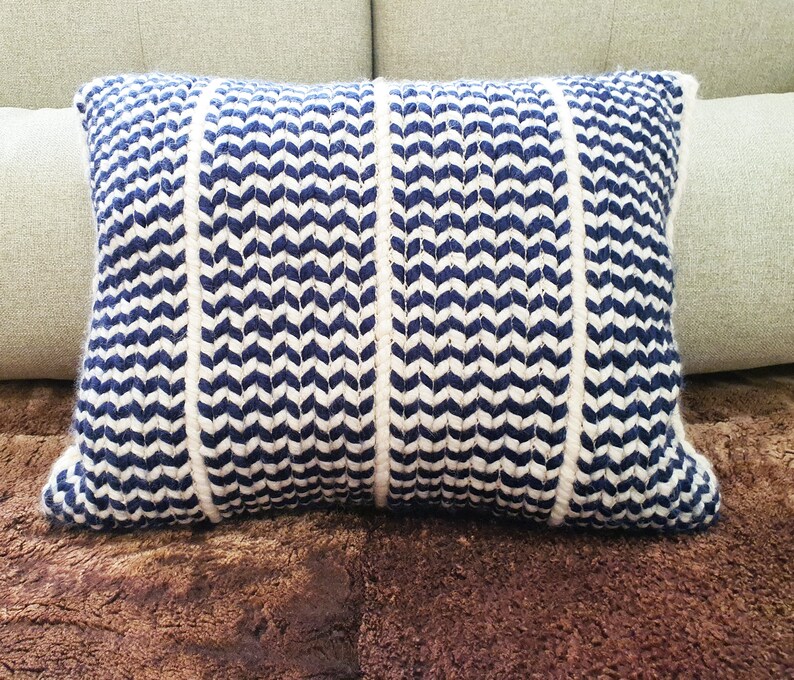 May include: A blue and white striped throw pillow with a chevron pattern. The pillow is made of a soft, textured fabric.