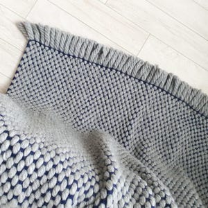 Edge detail of chunky knit blanket showing thick yarn loops and finishing.