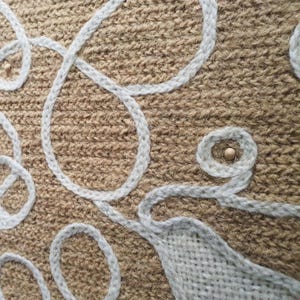 Close-up of wool embroidery showing dense stitches in a wall decorative panel, handmade.