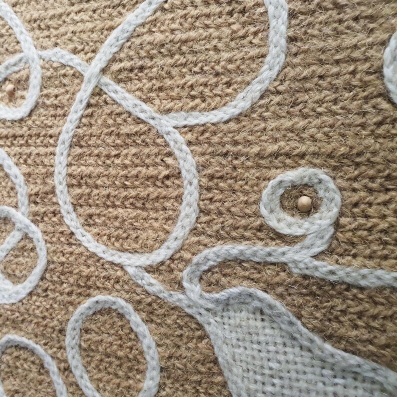 Close-up of wool embroidery showing dense stitches in a wall decorative panel, handmade.