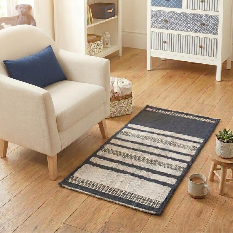 ven rug in blue and white stripes placed near an armchair in a modern living room.
