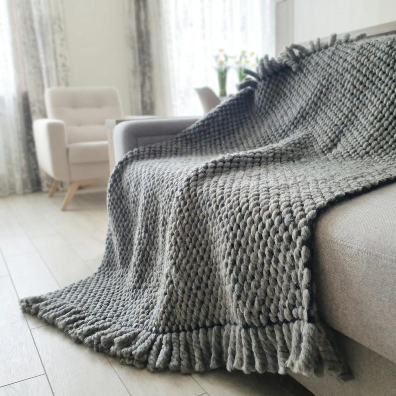 Chunky knit blanket placed on a couch with relaxed folds and textured surface