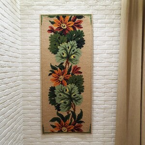 Wool wall hanging with floral embroidery and green leaves, handmade textile wall art with visible texture