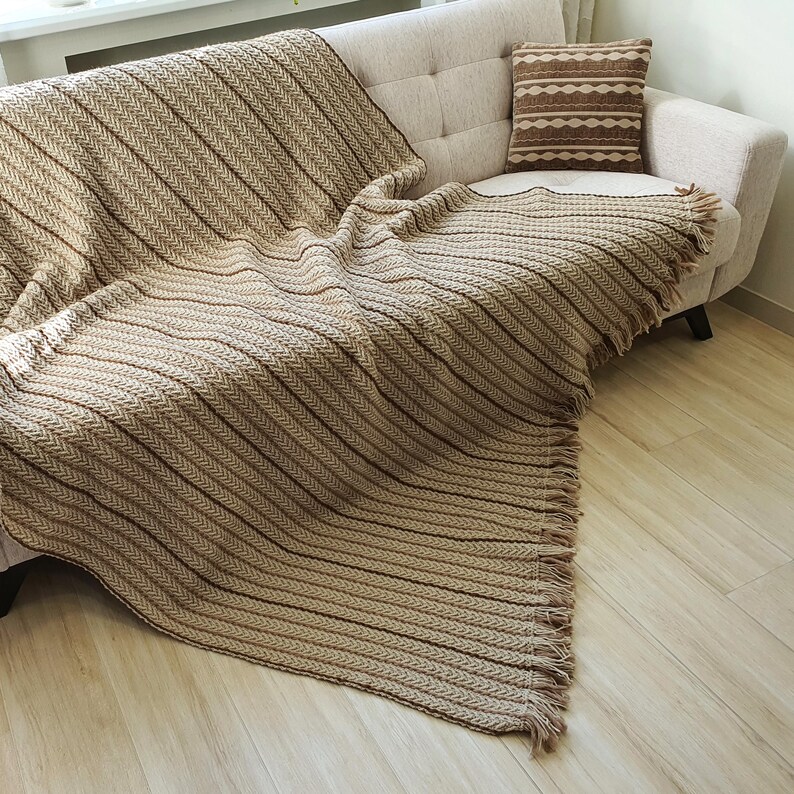 Handmade wool throw in beige color draped over a sofa, showing textured crochet pattern