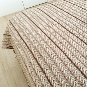 Textured crochet wool throw in beige color used as a sofa blanket in modern interior