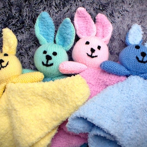 May include: Four knitted bunny baby blankets in yellow, pink, blue, and green. Each bunny has a different colored blanket.