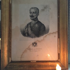Puede incluir: Un retrato enmarcado en blanco y negro de un hombre con uniforme militar. El retrato está titulado "CARLO ALBERTO Re di Sardegna" y presenta un escudo de armas en la parte inferior.