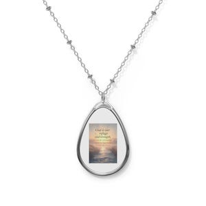 May include: Silver oval pendant necklace. The pendant has a framed image of a sunset over water with the text "God is our refuge and strength, a very present help in trouble."