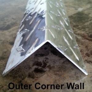 Puede incluir: Un diseño de pared de esquina exterior de metal plateado con un patrón de placa de diamante. El diseño está hecho de dos piezas de metal que se unen en un ángulo de 90 grados. El metal es brillante y tiene un ligero brillo. El diseño se llama "Outer Corner Wall Design".