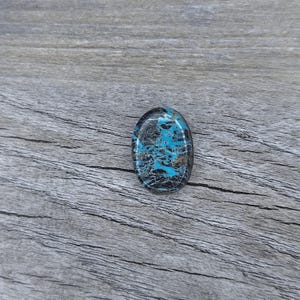May include: A blue and black oval-shaped cabochon gemstone with a marbled pattern.