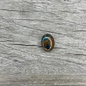 May include: A smooth, oval-shaped stone with a blue and brown marbled pattern.