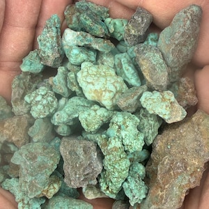 May include: A collection of raw turquoise stones in various shapes and sizes. The stones display a range of colors, from vibrant teal to muted greens and browns. The rough texture and natural variations highlight the organic beauty of the gemstones.