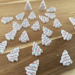 May include: A collection of white Christmas tree ornaments with red and green patterned designs.