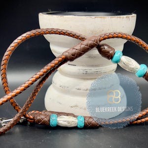 May include: A brown leather dog leash with turquoise and silver beads. The leash has a metal clasp.
