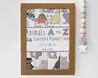 May include: A brown box with a clear plastic window showing a set of 26 illustrated alphabet cards featuring animals. The box has the text "Animals A TO Z 26 Illustrated Alphabet Cards by Pipit & Fox made in USA".