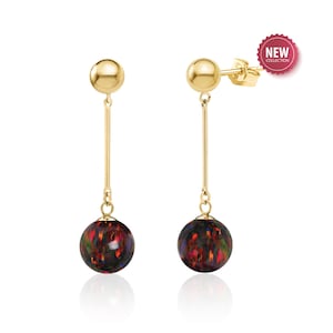 May include: A pair of gold drop earrings with black opal spheres. The earrings have a simple, elegant design and are perfect for everyday wear.