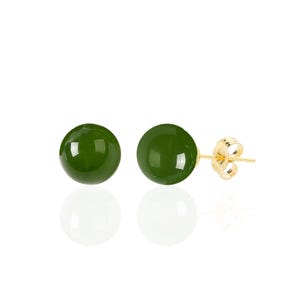 May include: A pair of green jade stud earrings with gold settings. The earrings are round and have a smooth, polished finish.
