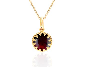 May include: A gold-colored necklace with a round, dark red pendant. The pendant is framed by a decorative, scalloped edge. The chain and pendant loop are also gold-colored, creating a cohesive and elegant design.