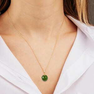 May include: A gold chain necklace with a round green jade pendant.