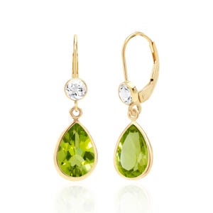 May include: A pair of gold-colored drop earrings. Each earring features a round, clear gemstone at the top and a pear-shaped, light green gemstone below. The earrings have a lever-back closure.