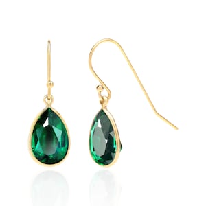 May include: A pair of gold teardrop earrings with green gemstone accents.