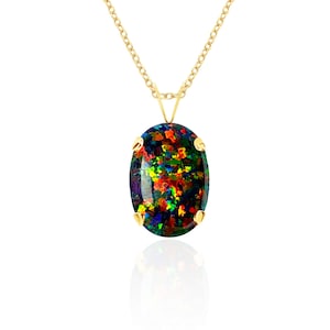 May include: A gold chain necklace featuring an oval-shaped black opal pendant. The gemstone displays a vibrant play of color with flecks of red, green, and yellow against a dark background, secured in a four-prong yellow gold setting.