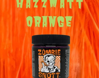 May include: A jar of "SNOTT Hair Dye" in the colour "Zombie" is shown against an orange background with the words "HAZZMATT ORANGE" in green. The jar features a skull graphic and the text "4 oz."