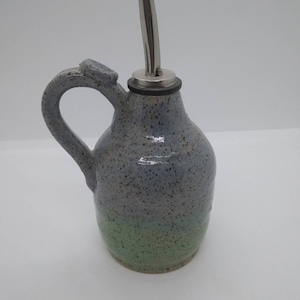 May include: A blue and green speckled ceramic oil and vinegar bottle with a stainless steel pour spout and a black rubber stopper.