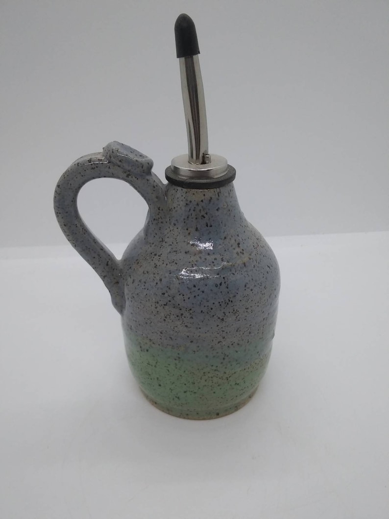 May include: A blue and green speckled ceramic oil and vinegar bottle with a stainless steel pour spout and a black rubber stopper.