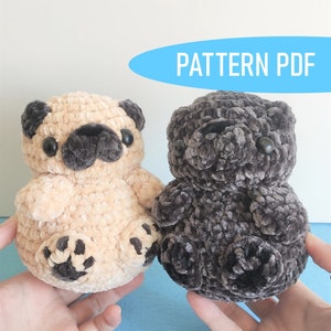 May include: Two crocheted plush pug dog toys. One is beige with brown accents and the other is dark gray.  The toys are being held in the hands of a person.  PATTERN PDF.