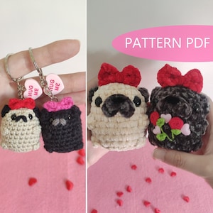 Pode incluir: Dois chaveiros de cão pug de crochê com laços vermelhos e rosa. Os chaveiros estão presos a um chaveiro prateado com um amuleto em forma de coração que diz "Hug Me".