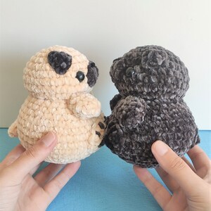 May include: Two crocheted plush toys shaped like pugs. One is beige and the other is dark gray.
