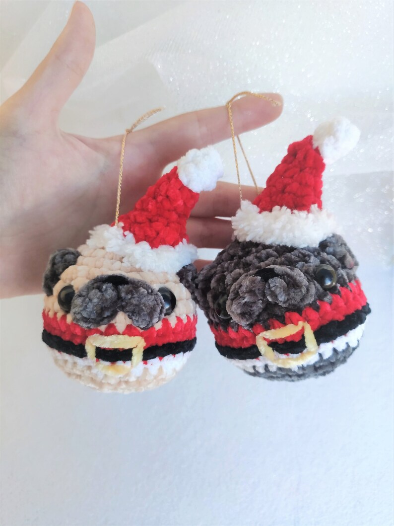 Pu&ograve; includere: Due ornamenti di carlino all'uncinetto con cappelli di Babbo Natale e abiti rossi e bianchi. I carlini sono beige e grigi.