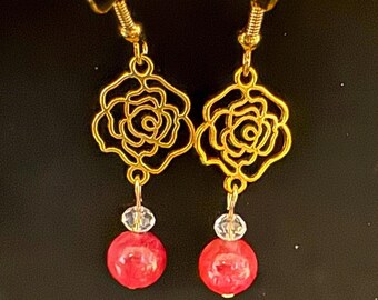 May include: Gold earrings with a rose design and a red bead dangle.