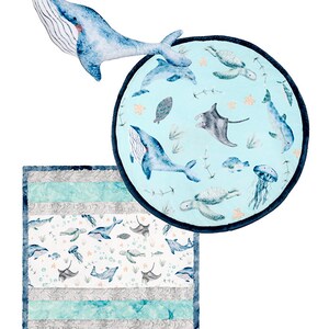 May include: A blue whale plush toy with a white and blue patterned baby blanket. The blanket features a variety of sea creatures including whales, turtles, manta rays, and jellyfish.