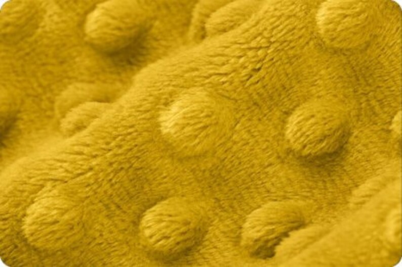 May include: Close-up of a yellow textured fabric with a raised dot pattern. The fabric is soft and plush.