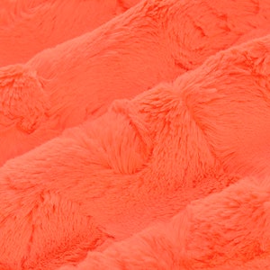 May include: Close-up of a bright orange fluffy fabric with a soft, plush texture.