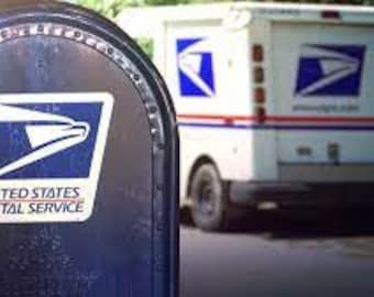 May include: A blue mailbox with the United States Postal Service logo and a white mail truck in the background.