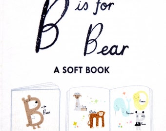 Pode incluir: Um livro macio para bebês com a letra B e a palavra "Urso" na capa. O livro está aberto para mostrar ilustrações de um urso, um cordeiro, um macaco, um narval e um panda.