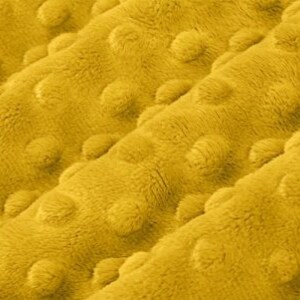 May include: Close-up of a yellow fabric with a textured, bumpy surface. The fabric has a soft, plush feel.