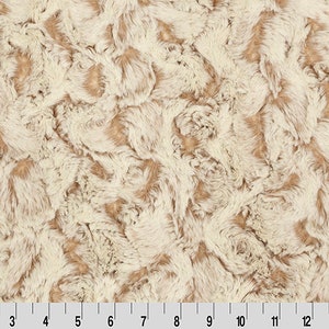May include: A close-up of a soft, fluffy fabric with a swirling pattern in shades of beige and cream.